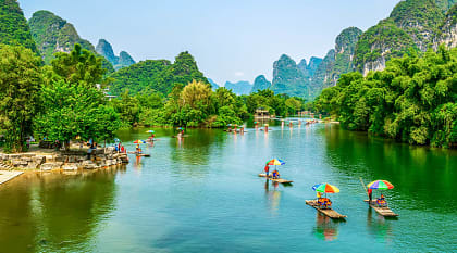 Tourists on bamboo boats floating down the Li River between the karsts in Guilin, China