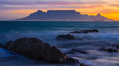 Silhouette of Table Mountain against sunset sky and ocean waves in Cape Town, South Africa Silhouette of Table Mountain against sunset sky and ocean waves in Cape Town, South Africa