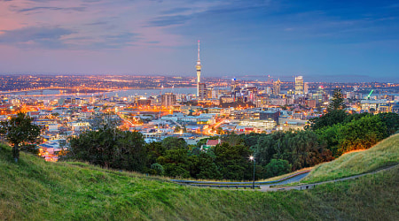Sky Tower in Auckland, New Zealand Auckland cityscape at dusk viewed from Mount Eden grassy slopes.