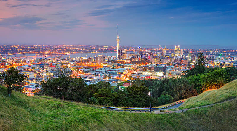 Auckland cityscape at dusk viewed from Mount Eden grassy slopes.