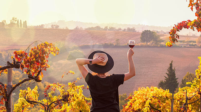 Tuscany, Italy Woman raising a glass of wine, enjoying the view at sunset in Tuscany