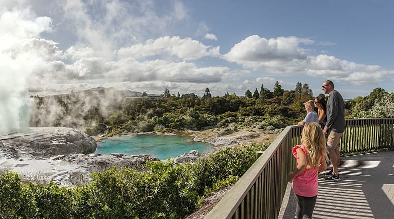 Te Puia in Rotorua, New Zealand. Photo courtesy of Destination Rotorua Family veiwing the gothermal lake and geyser at Te Puia in Rotorua, New Zealand
