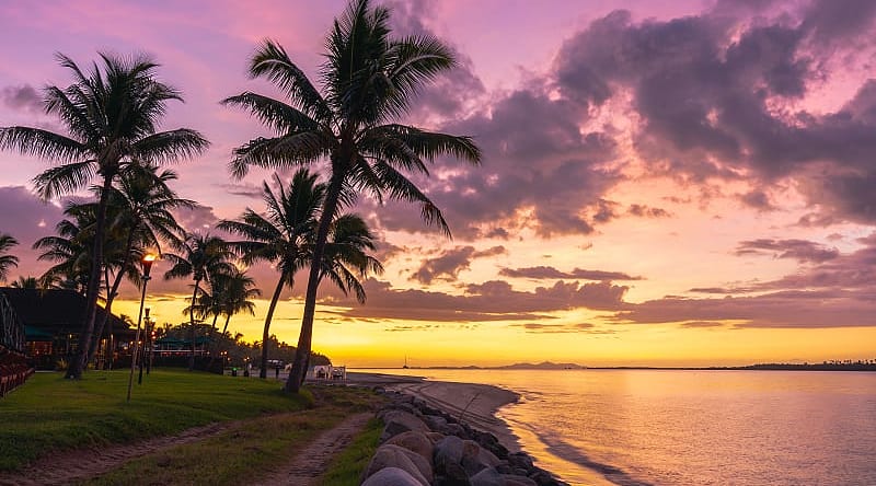 A Perfect Romantic Getaway to Fiji & Australia Palm tree silhouette against a beautiful sunset on the fijian coast