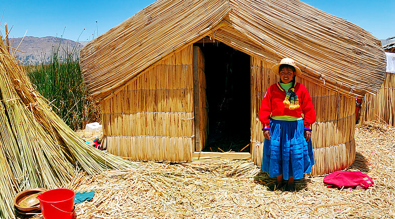 A girl standing on a floating Uros island standing in front of her home in Lake Titicaca, Peru. A girl standing on a floating Uros island standing in front of her home in Lake Titicaca, Peru.
