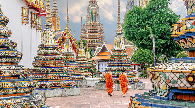 Wat Pho Temple in Bangkok, Thailand Two monks in colorful orange robes walking through Wat Pho Temple in Bangkok, Thailand