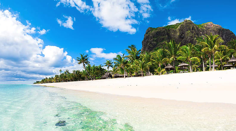 Beautiful view of the resort on le morne peninusala mauritius with clear ocean, white sand, palms and blue sky on the