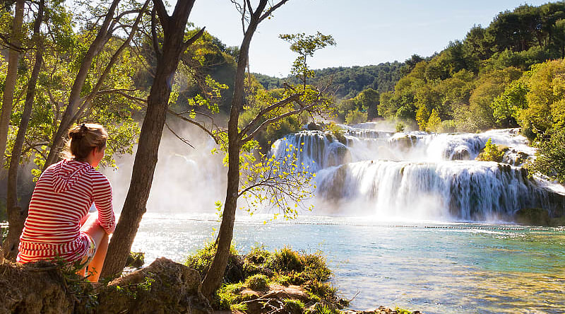 Croatia Tour for Seniors: Sophistication and Adventure Woman traveler relaxing and viewing the waterfalls in Krka National Park, Croatia