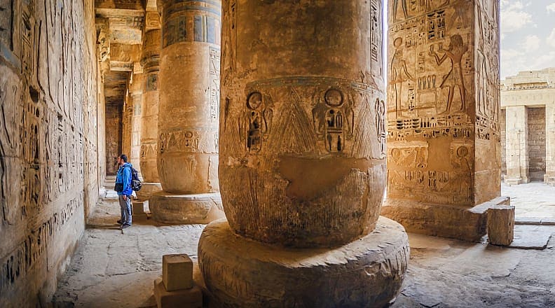 Traveler viewing hieroglyphs on the walls of the Temple of Medinet Habu in Egypt Traveler viewing hieroglyphs on the walls of the Temple of Medinet Habu in Egypt