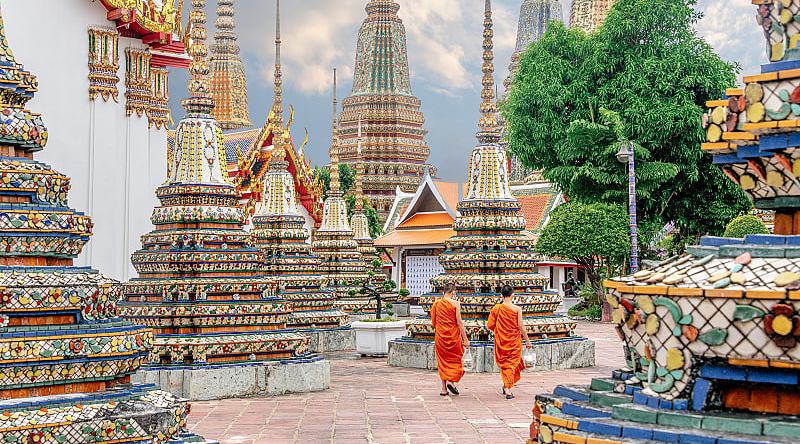 Wat Pho Temple in Bangkok, Thailand Two monks in colorful orange robes walking through Wat Pho Temple in Bangkok, Thailand