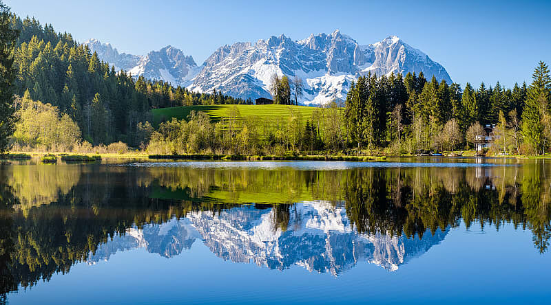 Idyllic alpine scenery, snowy mountains mirroring in a small lake in Tyrol, Austria.