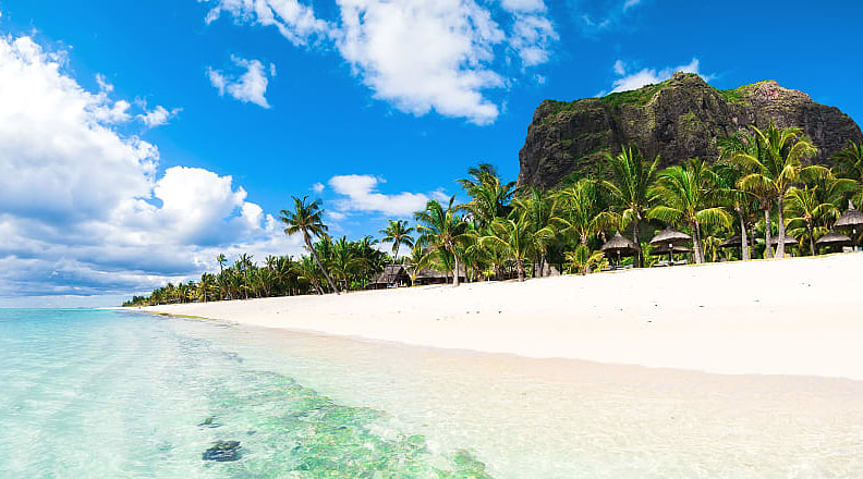 Beautiful view of the resort on le morne peninusala mauritius with clear ocean, white sand, palms and blue sky on the