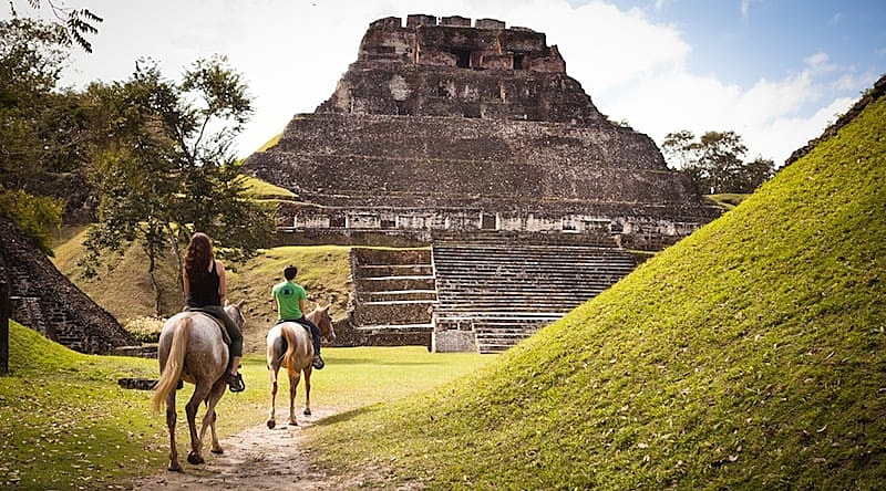 Couple horseback riding to the ancient Maya ruins of Xunantunich in Cayo District, Belize