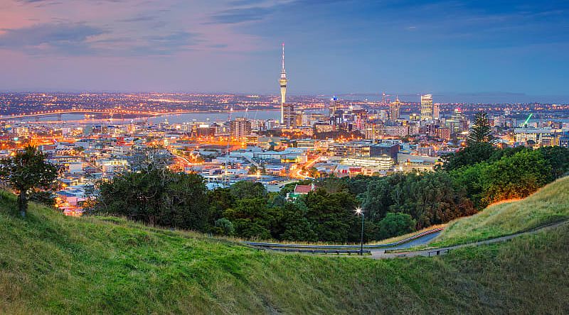 Sky Tower in Auckland, New Zealand Auckland cityscape at dusk viewed from Mount Eden grassy slopes.