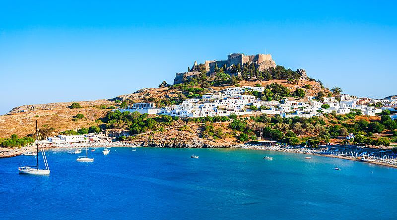 Rhodes, Greece Lindos acropolis on hill above white houses and blue ocean bay in Rhodes, Greece