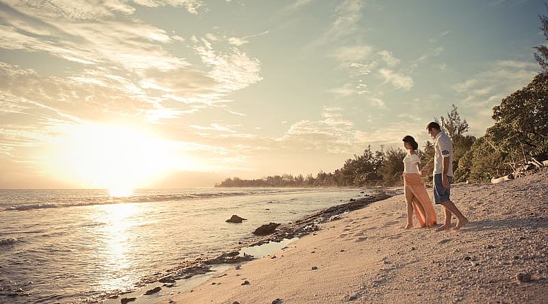 Honeymoon couple on the beach in Moorea, Tahiti.  Photo courtesy Tahiti Tourisme/Hélène Havard