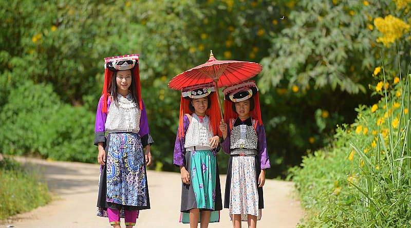 Three young Lahu Tribe girls in custom dress, smiling among the sunlight in Thailand. Three young Lahu Tribe girls in custom dress, smiling among the sunlight in Thailand.