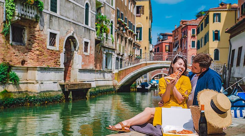 Couple enjoying a romantic picnic along a canal in Venice, Italy