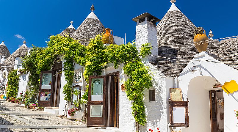 Beautiful town of Alberobello with trulli houses among green plants and flowers in the Apulia region of southern Italy.