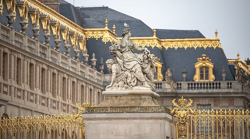 Statue and ornate architecture of Versailles in France.