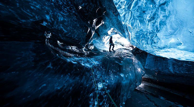 Essential Iceland Tour for Solo Travelers Mountain climber standing inside ice cave glacier