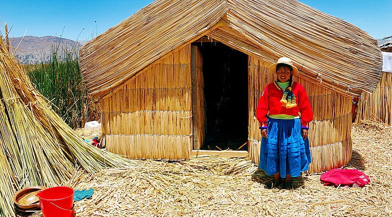 A girl standing on a floating Uros island standing in front of her home in Lake Titicaca, Peru. A girl standing on a floating Uros island standing in front of her home in Lake Titicaca, Peru.