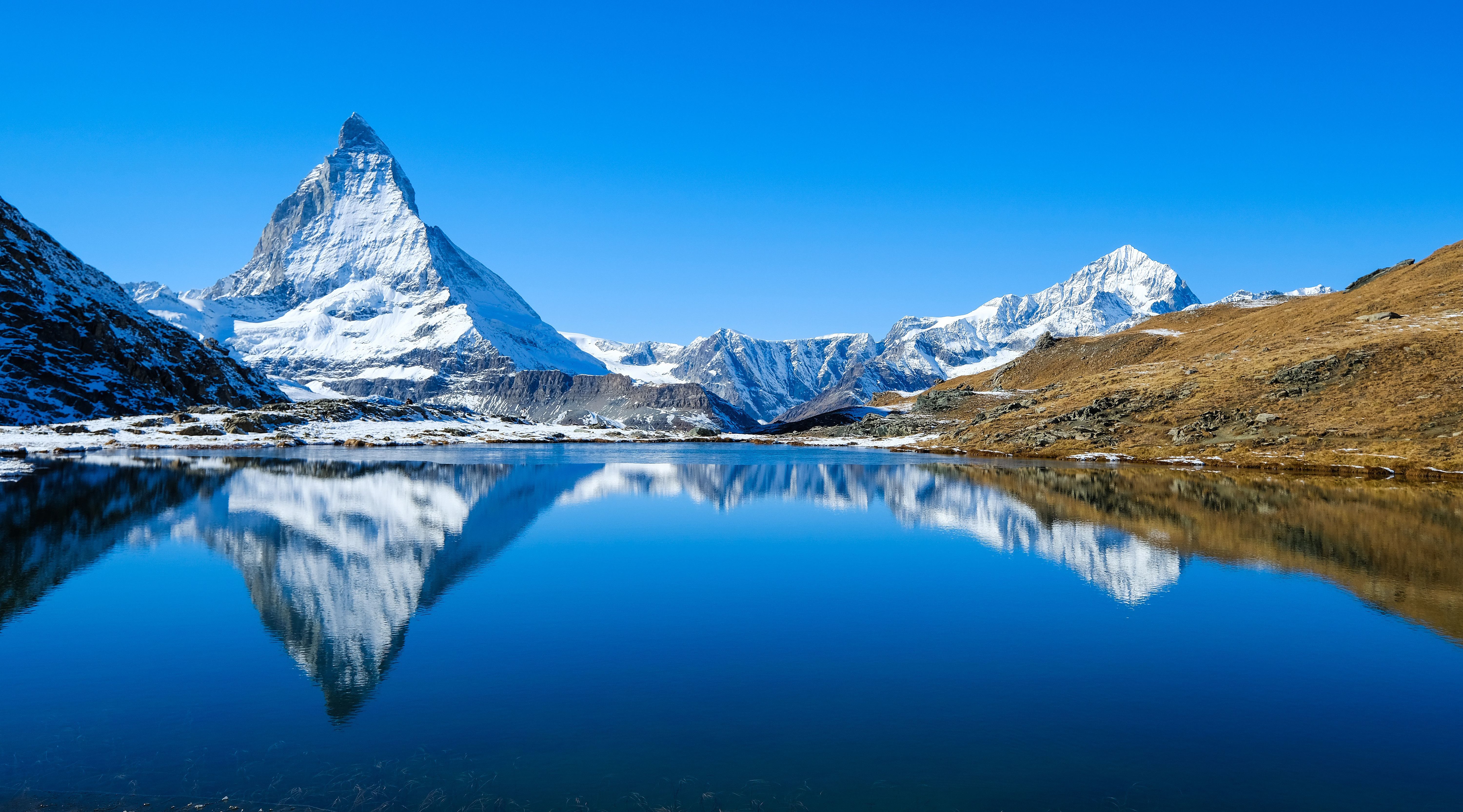 The Matterhorn summit is reflected in the glacial lake of the Swiss Alpine waters.