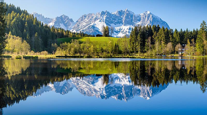 Idyllic alpine scenery, snowy mountains mirroring in a small lake in Tyrol, Austria.