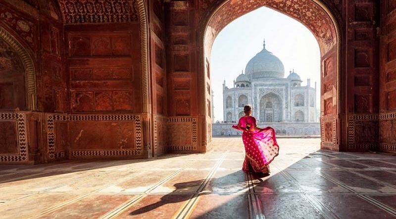 Woman in red sari admiring the Taj Mahal in Agra India
