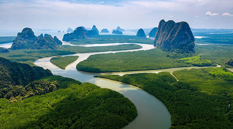 Aerial view of towering limestone cliffs and mangrove forest in Phang Nga Bay, Thailand.