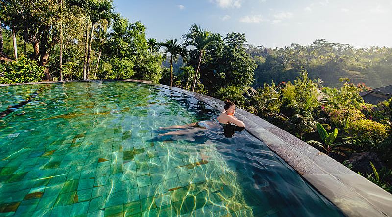 Woman lounging in an infinity pool at a luxury resort in Bali, Indonesia