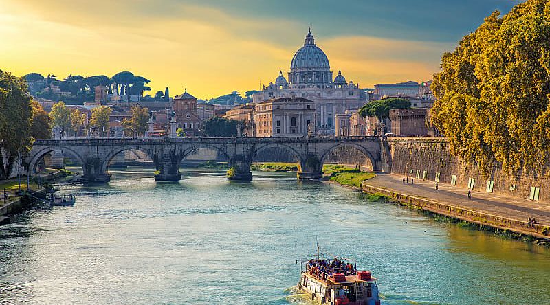 Boat sailing on Tiber River with Saint Peter's Basilica in Rome, Italy