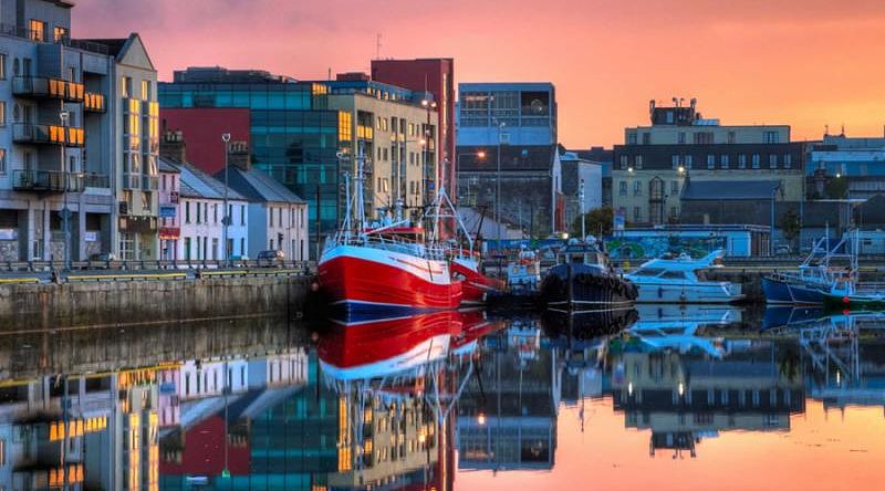 Boats in Galway dock at sunrise in Ireland.