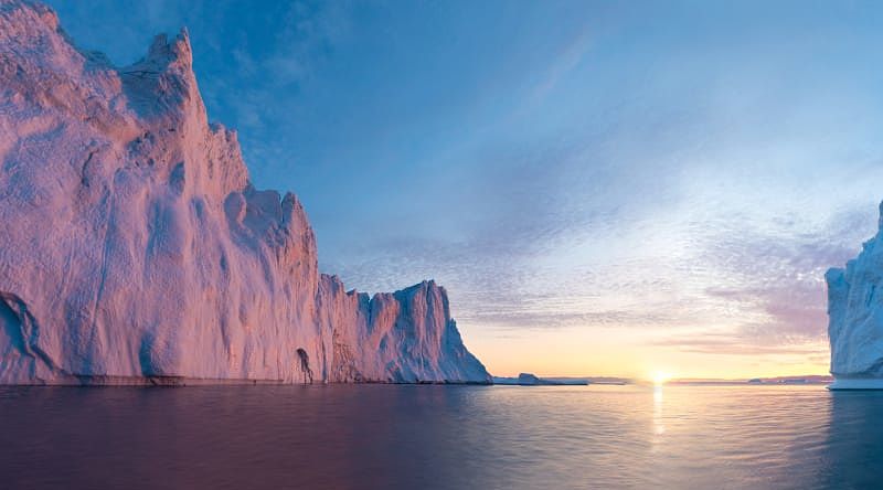 Early morning summer alpenglow lighting up icebergs during midnight season.