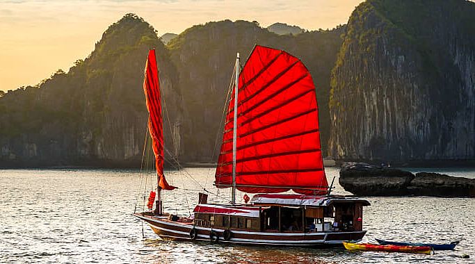 A red junk boat sailing in Ha Long Bay in Vietnam. A red junk boat sailing in Ha Long Bay in Vietnam.