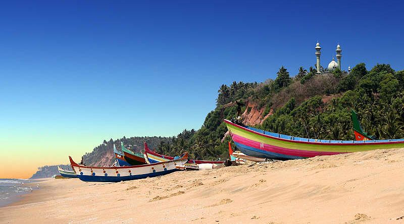 Colorful boats in front of Varkala South Cliff with mosque on top in Kerala, India. Colorful boats in front of Varkala South Cliff with mosque on top in Kerala, India.