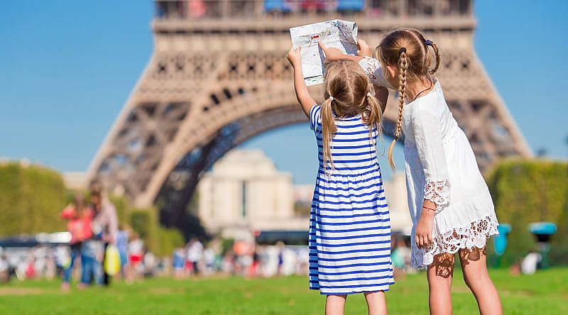 Little girls with a map of Paris on the background of the Eiffel tower, Paris