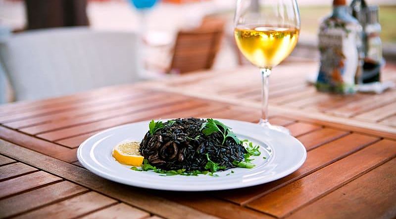 Black risotto with seafood and glass of white wine Black risotto with seafood and glass of white wine