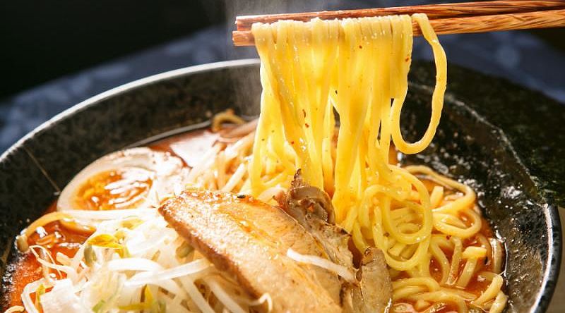 A bowl of miso ramen made with broth that has been seasoned with miso. Japan Tour - Chopsticks Scooping Noodles from Bowl of Miso Ramen