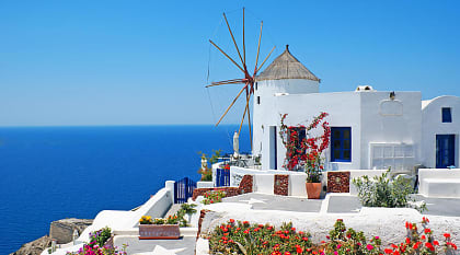 Windmill and white house with clear blue sky and ocean in Santorini
