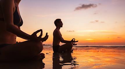 A couple practicing some meditation during a sunrise in French Polynesia.