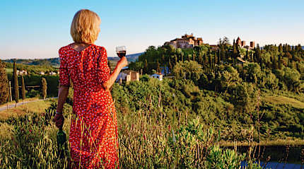 Mature woman with a glass of red wine, on vacation beside the hilltop village of Certaldo in the Tuscany region of Italy.