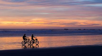 Couple biking on the beach at sunset in Costa Rica