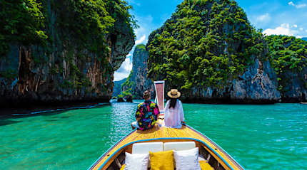 Couple on a traditional boat exploring turquoise waters and limestone cliffs in Krabi, Thailand