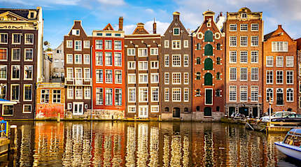 Amsterdam’s colorful canal houses reflect beautifully on the calm water.