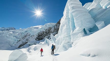 Two people hiking Tasman Glacier in Mount Cook National Park, New Zealand