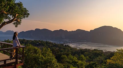 A woman standing at Phi Phi View Point watching the sunset