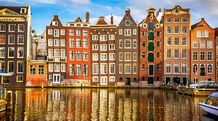 Amsterdam’s colorful canal houses reflect beautifully on the calm water.