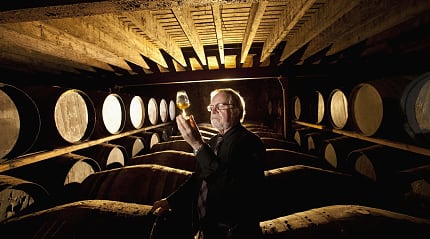 Worker testing whisky in distillery
