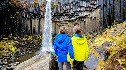 Young siblings at Svartifoss waterfall in Iceland