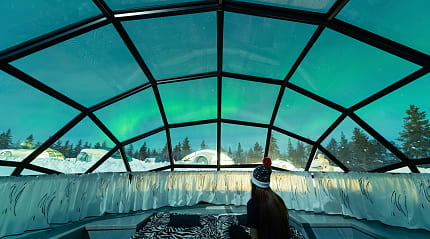Teen girl watching the Northern Lights from glass igloo in Lapland, Finland